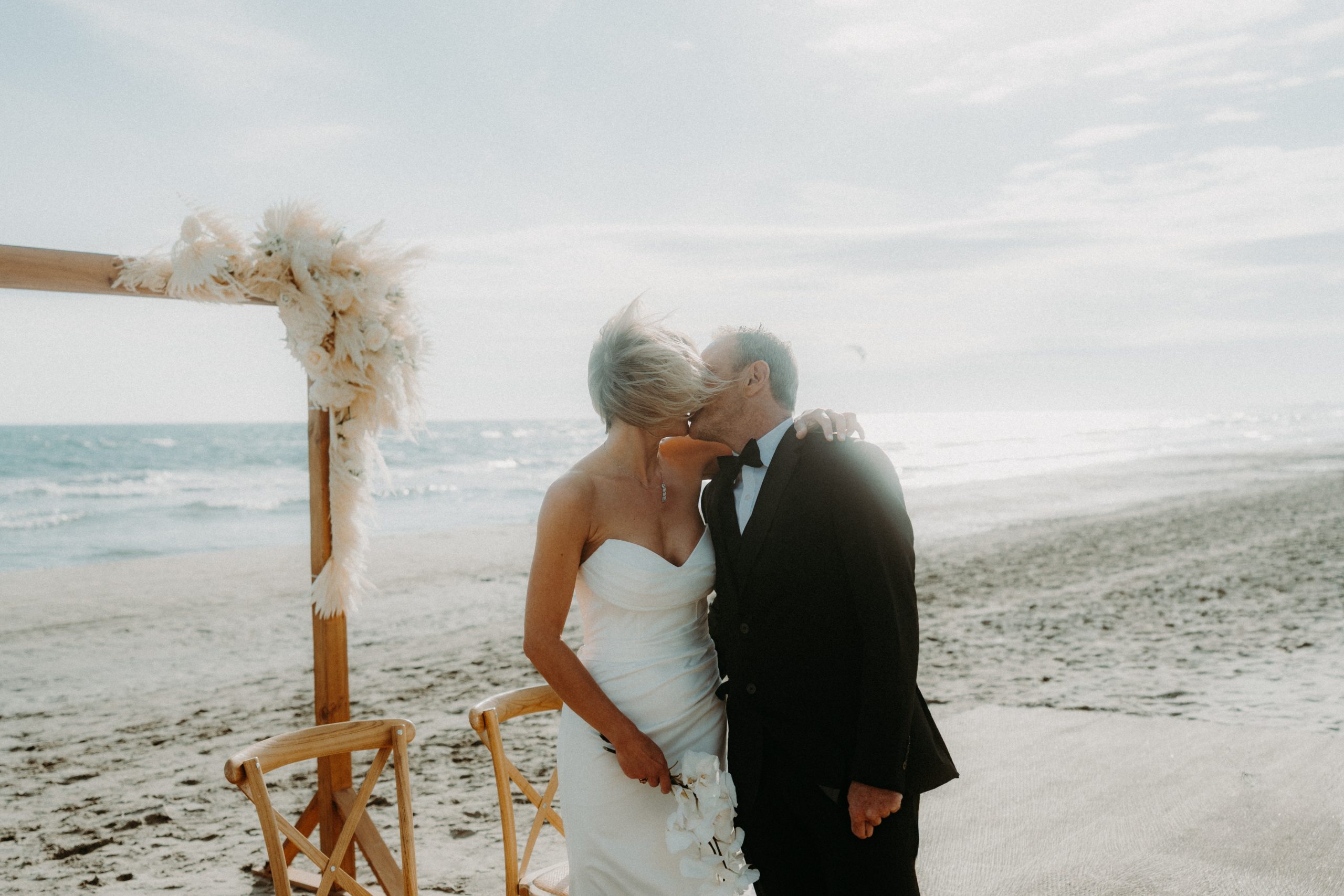 mariés s'embrassant lors de leur cérémonie sur la plage à effet mer à la grande motte