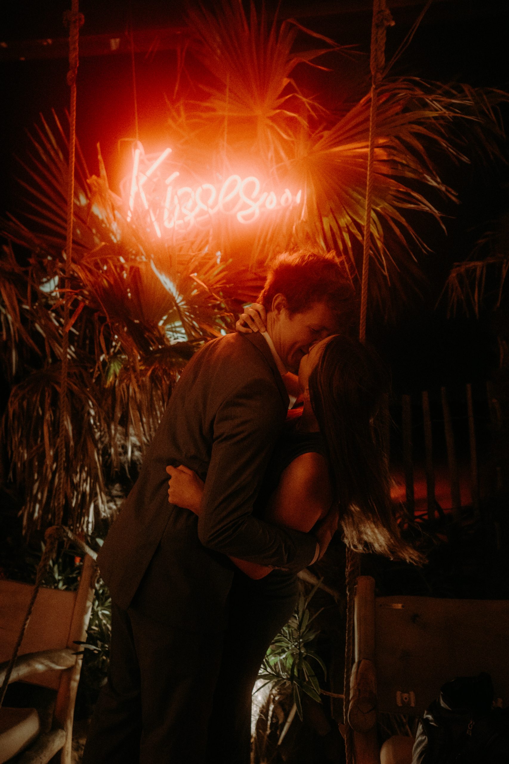 couple d'invités de mariage qui s'embrasse sous un néon Kisses au bar effet mer à la grande motte